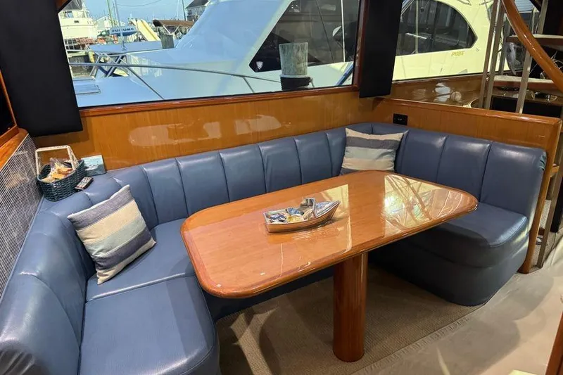 Slide: The Image of Luxurious interior of 2002 Viking 61 Enclosed Bridge yacht with blue seating and wooden table. - 90