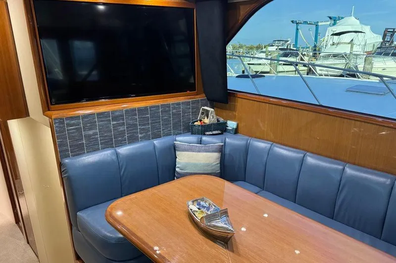 Slide: The Image of Luxurious interior of 2002 Viking 61 Enclosed Bridge yacht with blue seating and large TV. - 91