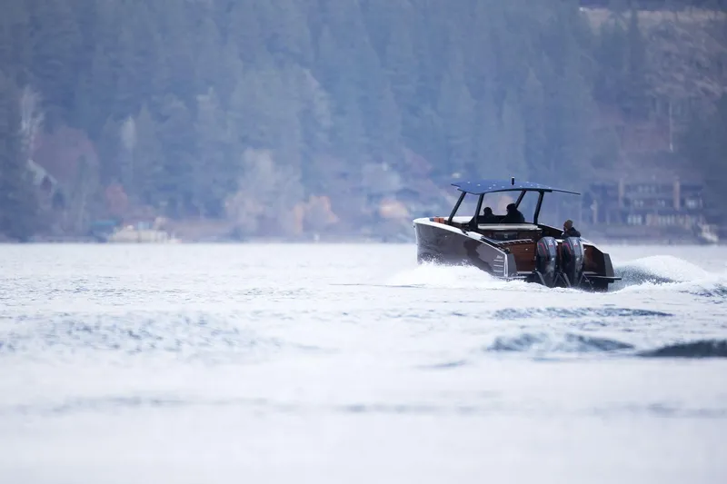 Slide: The Image of 2023 StanCraft 340 Hammerhead Center Console cruising on a serene lake with forested backdrop. - 9