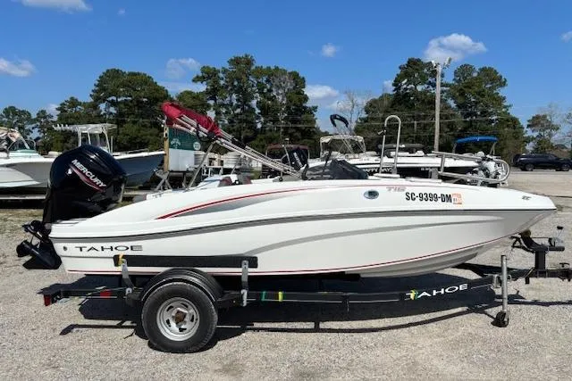 Slide: The Image of 2020 Tahoe T16 boat on trailer, parked outdoors under a clear blue sky. - 64