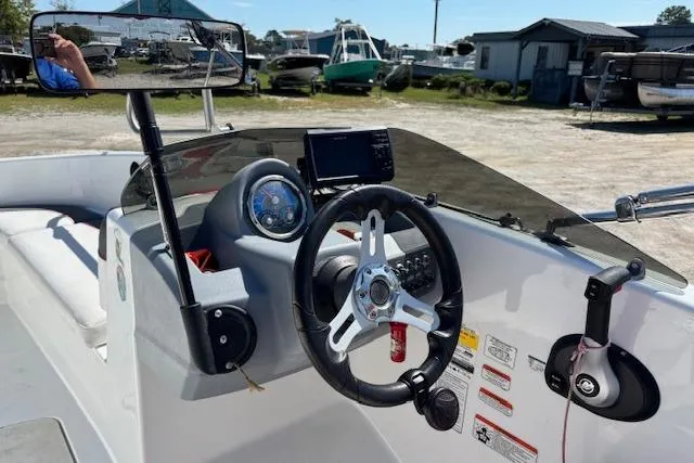 Slide: The Image of 2020 Tahoe T16 boat dashboard with steering wheel and control panel in a marina setting. - 74