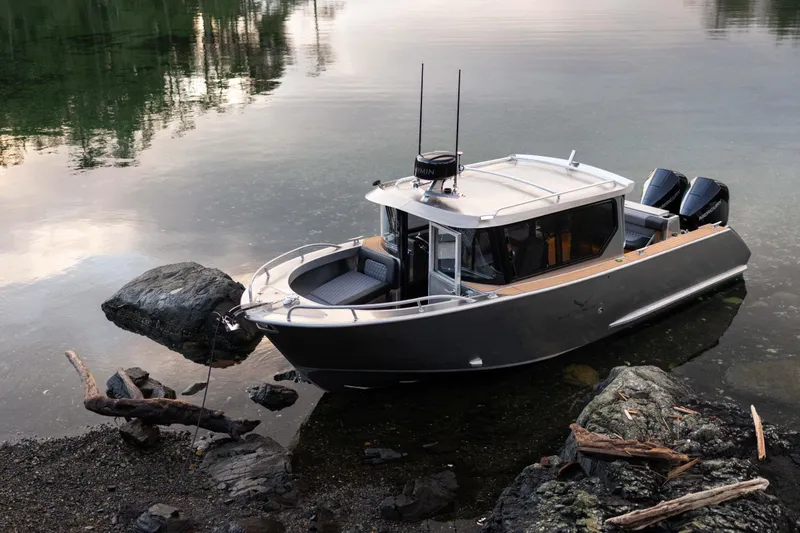 The Image of 2026 Jasper Marine Defender 22 boat docked on calm water near rocky shore. - 0