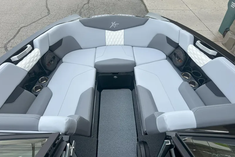 Slide: The Image of 2025 MasterCraft XT24 boat interior with gray and white seating, cup holders, and speakers. - 4