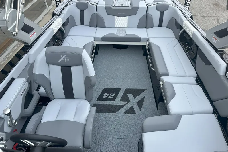 Slide: The Image of 2025 MasterCraft XT24 boat interior with luxurious gray seating and branded flooring. - 6