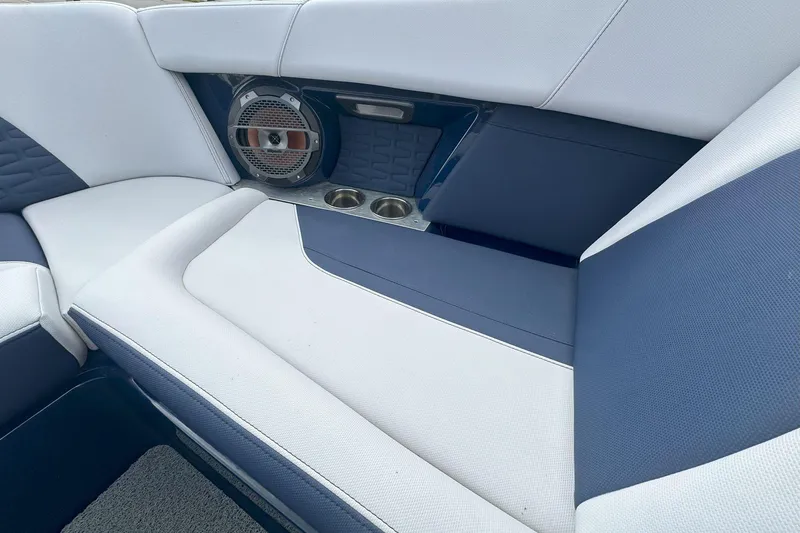 Slide: The Image of 2021 MasterCraft X24 boat interior with blue and white seating, speaker, and cup holders. - 10