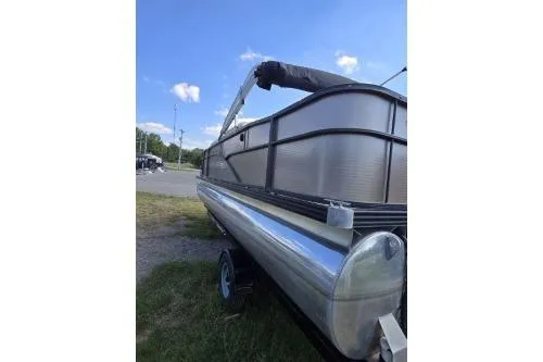 Slide: The Image of 2015 Manitou 20 Oasis Angler pontoon boat on trailer, under clear blue sky. - 5