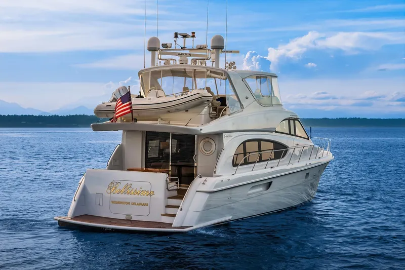 Slide: The Image of 2001 Hatteras 63 Cockpit Motor Yacht on serene water, rear view with American flag. - 28
