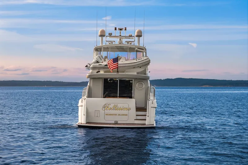 Slide: The Image of 2001 Hatteras 63 Cockpit Motor Yacht with dinghy and American flag on blue water. - 29
