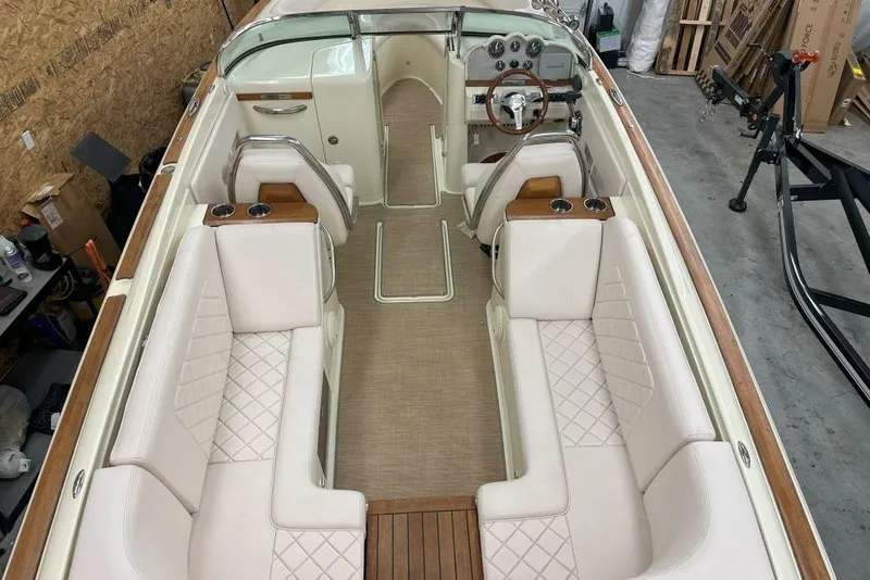Slide: The Image of 2018 Chris-Craft Launch 27 interior with white seating and wood accents in a garage setting. - 9