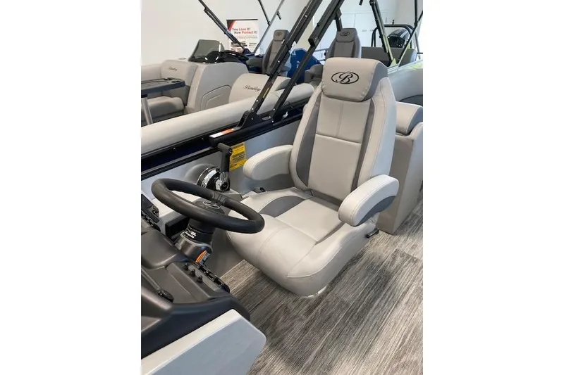Slide: The Image of 2026 Bentley Pontoons Legacy 243 Navigator captain's chair and steering wheel in a showroom. - 12
