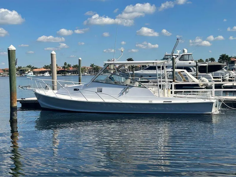 The Image of 1982 Robertson 3500 Custom Sportfish boat docked in a marina under a clear blue sky. - 0