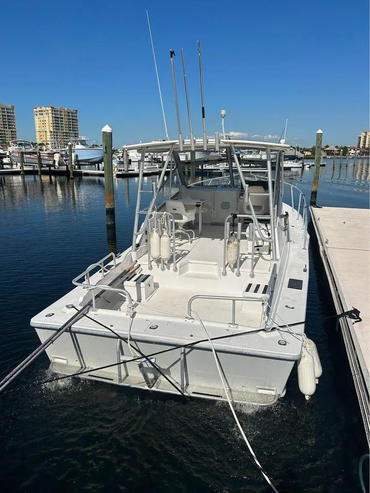 Slide: The Image of 1982 Robertson 3500 Custom Sportfish boat docked in a marina under clear blue skies. - 3