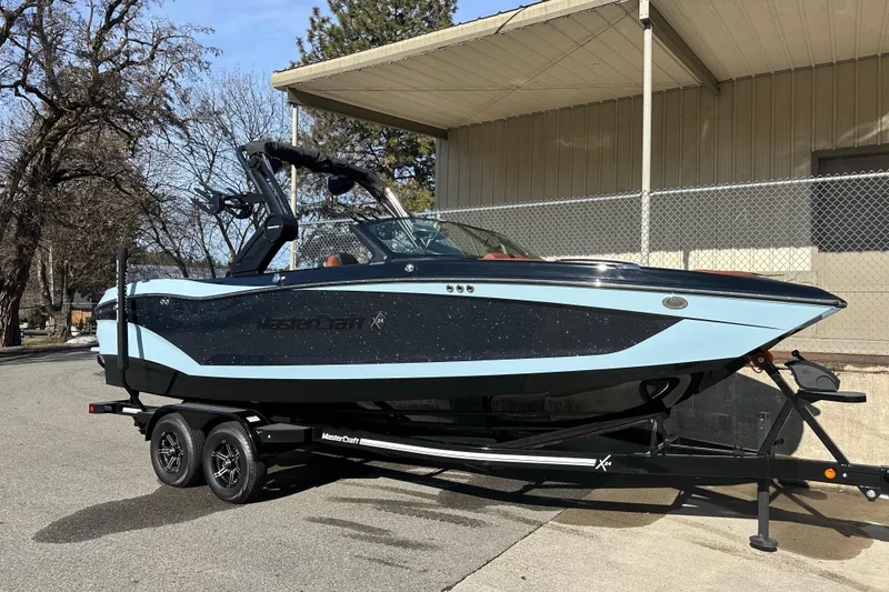 The Image of 2024 MasterCraft X24 boat on trailer, parked outdoors near a building. - 1