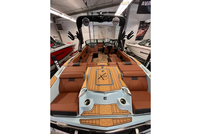 Slide: The Image of 2024 MasterCraft X24 boat interior with brown seating and sleek design in showroom. - 6