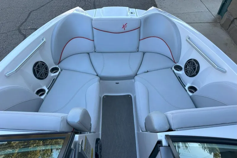 Slide: The Image of 2017 MasterCraft X23 boat interior with white seating, cup holders, and speakers. - 6