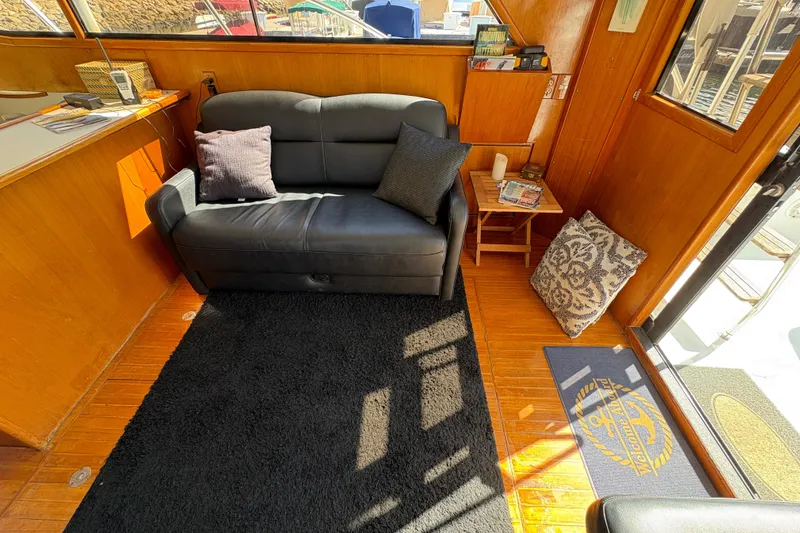 Slide: The Image of 1988 Ventare Sportfisher interior with black sofa, wooden paneling, and nautical decor. - 6