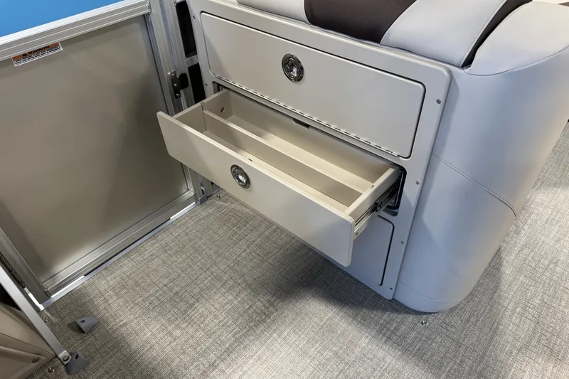 Slide: The Image of 2026 Avalon LSZ QL boat interior with open storage drawer on carpeted floor. - 9