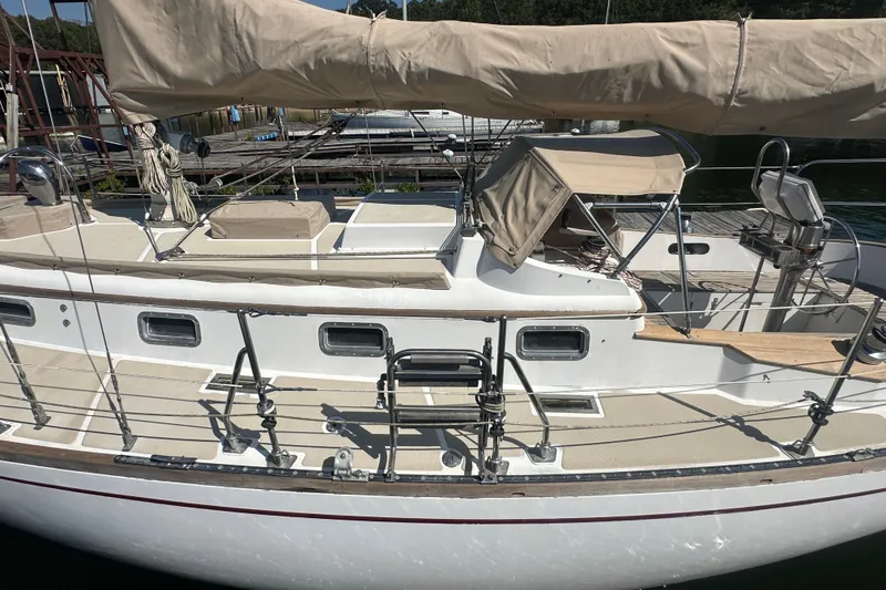 Slide: The Image of 1986 Mason 33 sailboat docked, featuring a covered deck and sleek design. - 13