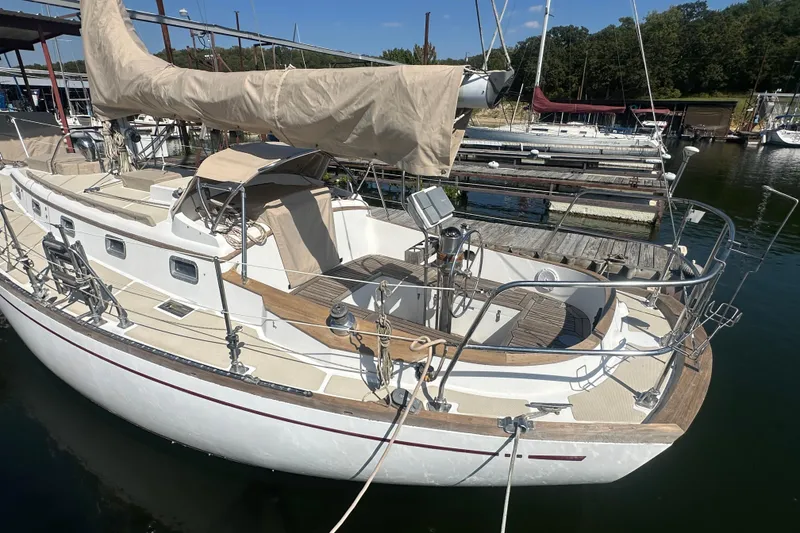 Slide: The Image of 1986 Mason 33 sailboat docked at a marina, featuring a classic design and beige sail cover. - 14