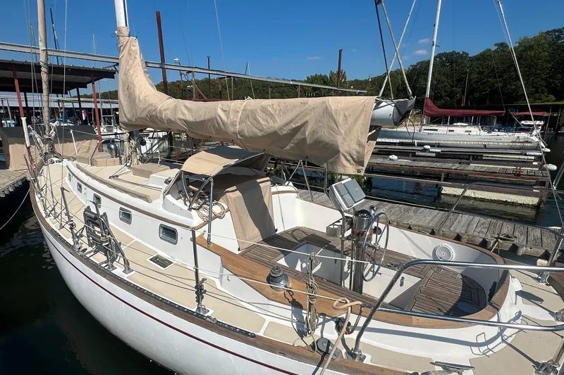 Slide: The Image of 1986 Mason 33 sailboat docked at marina, featuring beige covers and wooden deck. - 15