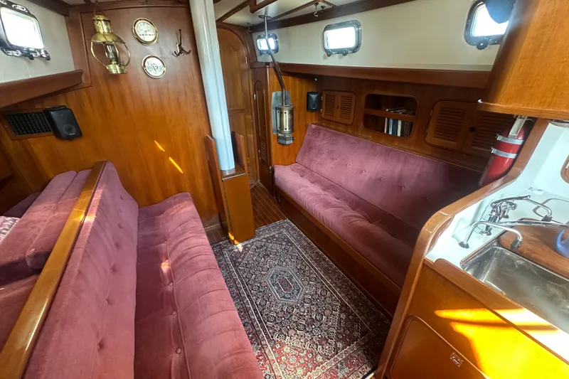 Slide: The Image of 1986 Mason 33 yacht interior with plush seating, wooden paneling, and nautical decor. - 21