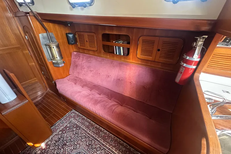 Slide: The Image of Interior of 1986 Mason 33 yacht with plush seating, wooden cabinetry, and fire extinguisher. - 22