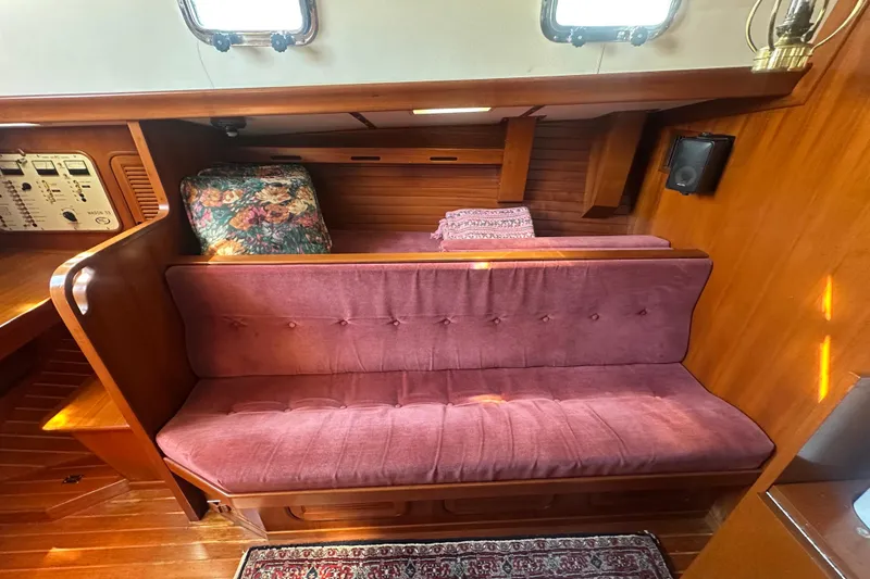 Slide: The Image of 1986 Mason 33 yacht interior with plush seating, floral cushion, and wooden paneling. - 24