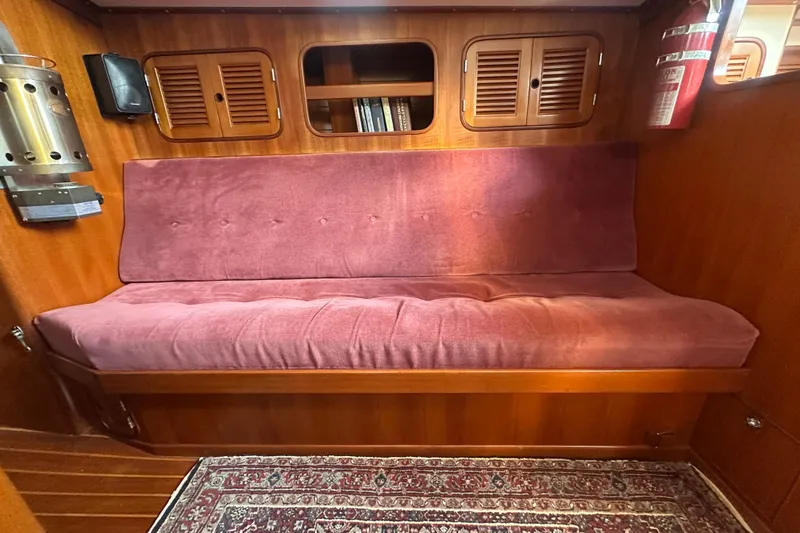 Slide: The Image of 1986 Mason 33 yacht interior with red cushioned seating and wooden cabinetry. - 26