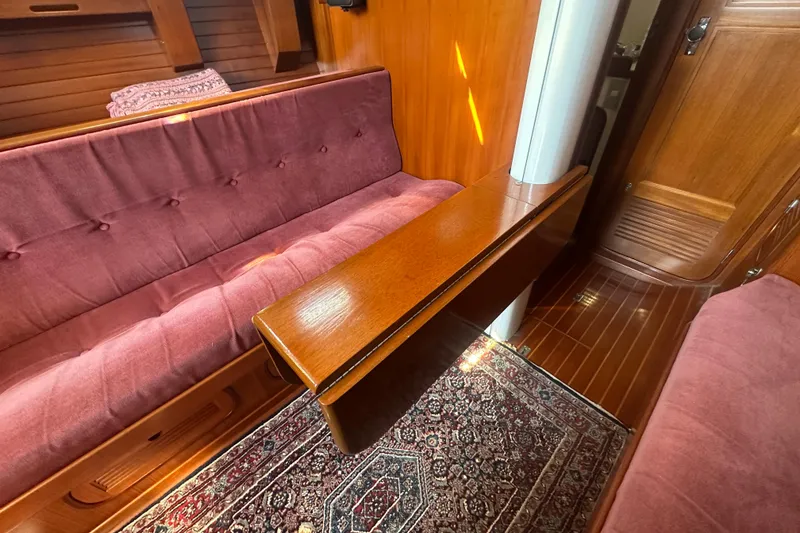 Slide: The Image of Interior of 1986 Mason 33 yacht with wooden table, pink seating, and patterned rug. - 27