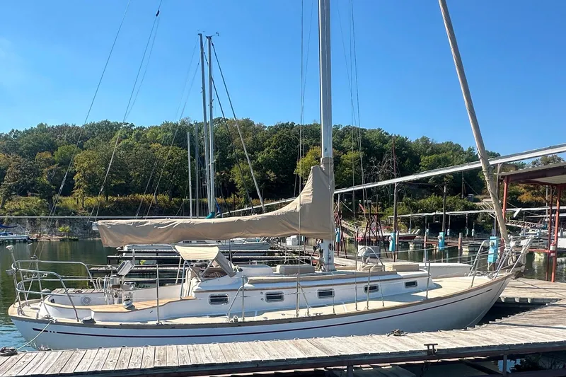 Slide: The Image of 1986 Mason 33 sailboat docked at a marina with lush green trees in the background. - 3