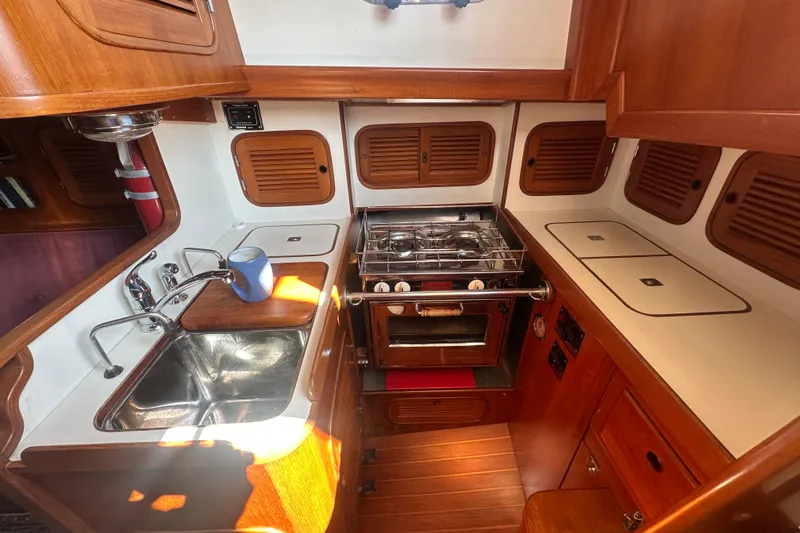 Slide: The Image of Compact kitchen in a 1986 Mason 33 yacht with stove, sink, and wooden cabinetry. - 30