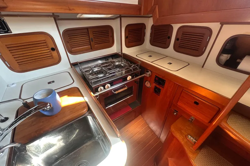 Slide: The Image of Compact kitchen in a 1986 Mason 33 yacht with wooden cabinetry and stainless steel sink. - 31