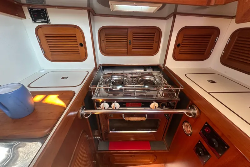 Slide: The Image of Compact kitchen area in a 1986 Mason 33 yacht with stove and wooden cabinets. - 35