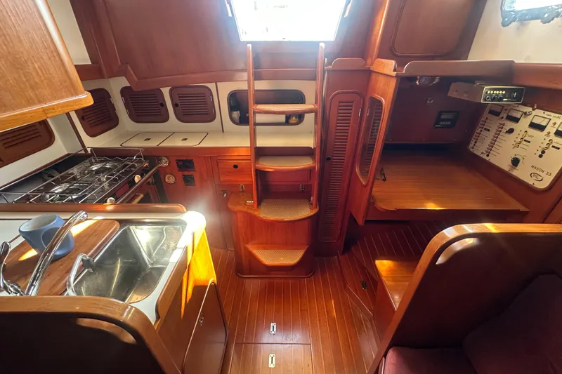 Slide: The Image of 1986 Mason 33 yacht interior with wooden cabinetry, kitchen, and navigation station. - 40