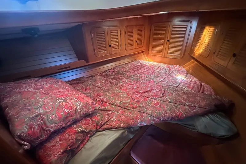 Slide: The Image of Cozy cabin interior of 1986 Mason 33 sailboat with patterned bedding and wooden storage. - 42