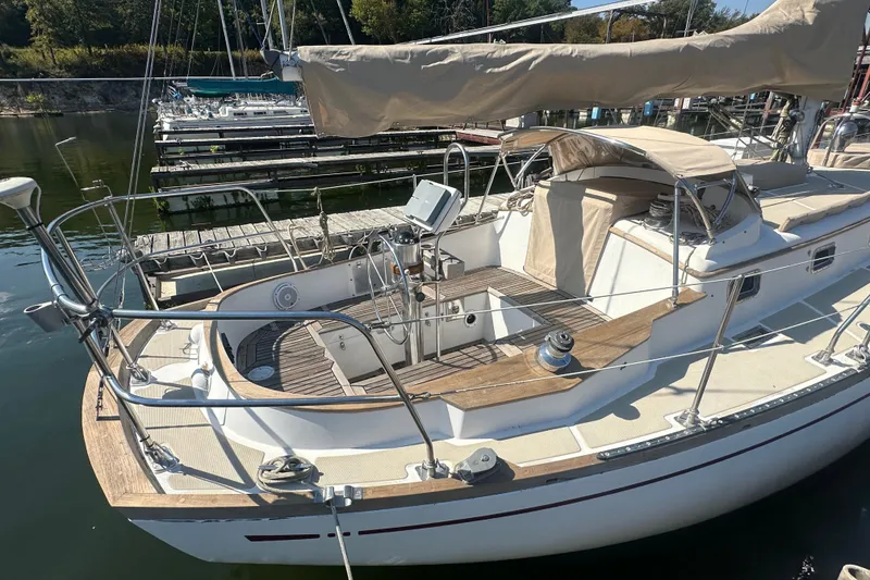 Slide: The Image of 1986 Mason 33 sailboat docked at marina, featuring wooden deck and beige covers. - 7