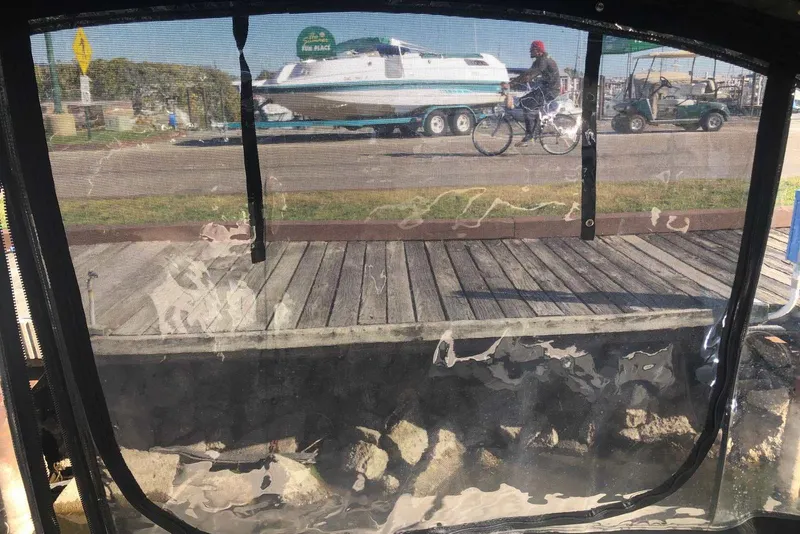 Slide: The Image of View through a boat's clear cover, showing a dock and a cyclist passing by. - 21