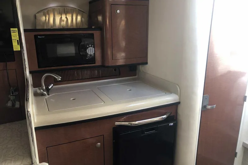 Slide: The Image of 2005 Sea Ray 280 Sundancer kitchenette with microwave, sink, and compact fridge. - 36