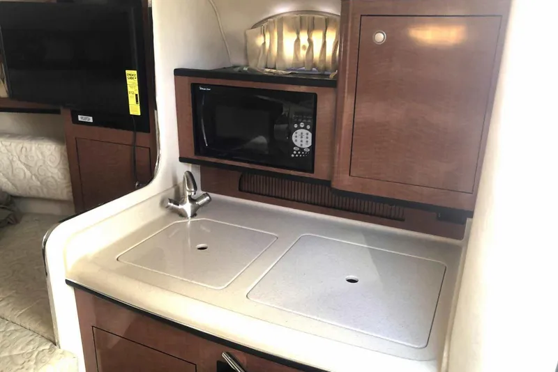 Slide: The Image of 2005 Sea Ray 280 Sundancer interior kitchen with sink, microwave, and wooden cabinetry. - 37