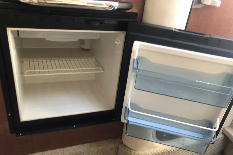 Slide: The Image of Open mini fridge inside 2005 Sea Ray 280 Sundancer boat, showing empty shelves. - 41