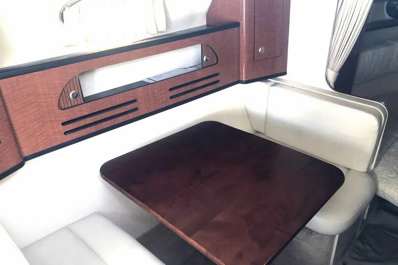 Slide: The Image of Interior of 2005 Sea Ray 280 Sundancer with wooden table and cushioned seating. - 48