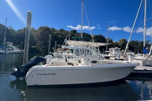 Slide: The Image of 2021 Sailfish 242 CC boat docked in a marina under a clear blue sky. - 0