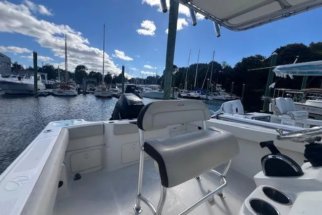 Slide: The Image of 2021 Sailfish 242 CC boat interior at marina, featuring seating and console. - 7