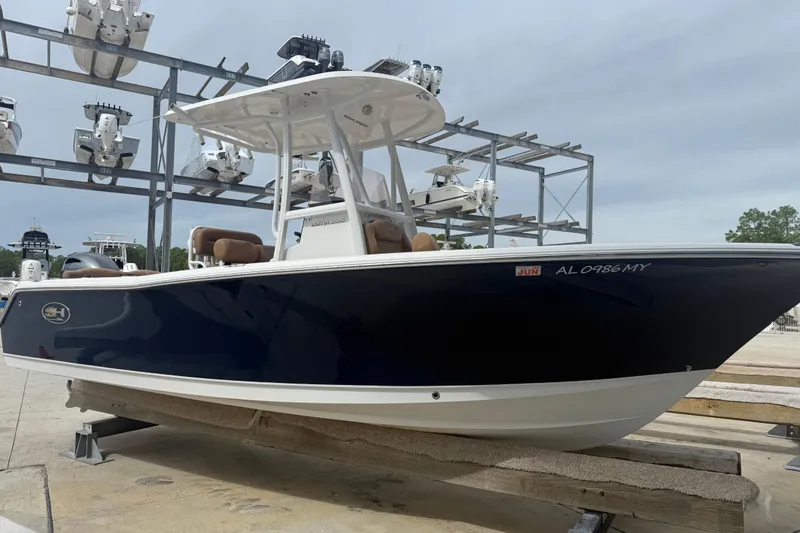 Slide: The Image of 2017 Sea Hunt Ultra 225 boat in storage, blue hull, white top, docked on a platform. - 0