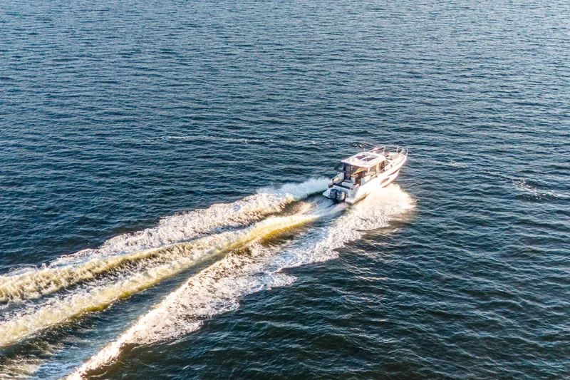 Slide: The Image of 2021 Jeanneau NC 1095 cruising on open water, leaving a wake behind. - 14