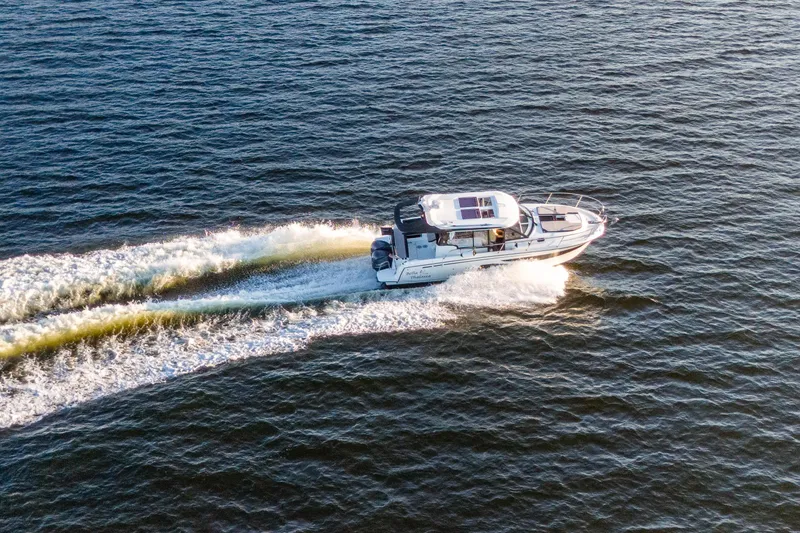 Slide: The Image of 2021 Jeanneau NC 1095 cruising on open water, creating a dynamic wake. - 15