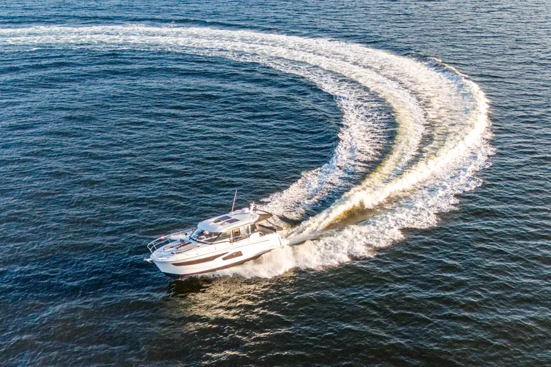 Slide: The Image of 2021 Jeanneau NC 1095 cruising on open water, creating a dynamic wake pattern. - 17