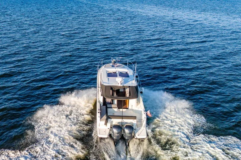 Slide: The Image of 2021 Jeanneau NC 1095 cruising on open water, rear view with twin engines. - 20