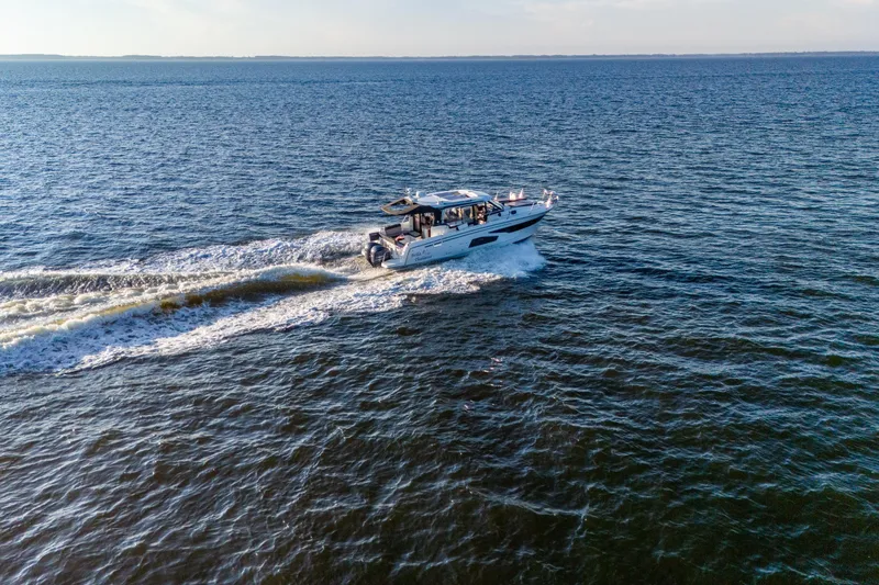 Slide: The Image of 2021 Jeanneau NC 1095 cruising on open water, creating a wake behind. - 23