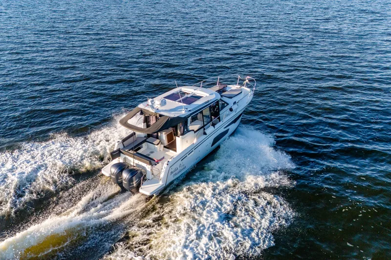 Slide: The Image of 2021 Jeanneau NC 1095 motorboat cruising on open water, rear view. - 3